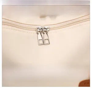 Close-up of premium nylon fabric with silver dual zippers and logo on a casual beige tote