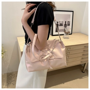 Dettaglio della borsa a tracolla rosa chiaro con fiocco decorativo e doppie catene