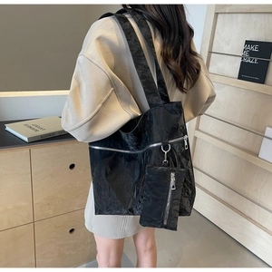 Close-up of black glossy wrinkled tote bag with matching detachable pouch detail