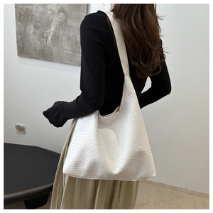 Detailed view of a white woven texture Hobo bag worn by a model in a minimalist setting