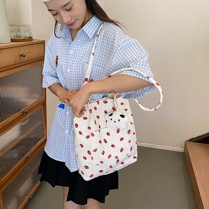 Top view of corduroy tote bag with strawberry print and cute panda plush keychain