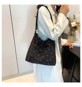 Detail view of black corduroy tote bag with strawberry pattern and drawstring closure