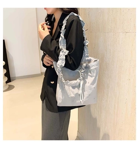 Detail of light grey pleated tote bag featuring ruffle strap and shimmering rhinestones