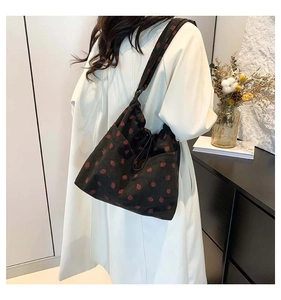 Detail of black corduroy tote bag featuring red strawberry embroidery and drawstring closure