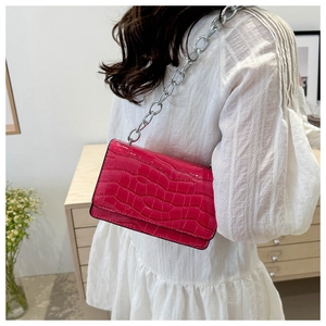 Detail of fuchsia crocodile embossed crossbody bag with chunky silver chain strap