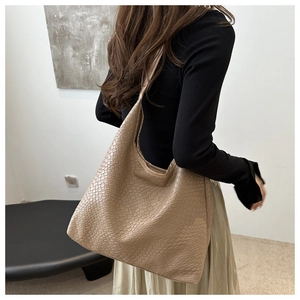 Detail of a large beige woven hobo tote bag worn over the shoulder for a retro style