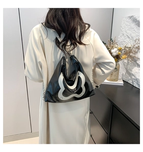 Chic black and white patent leather tote bag with abstract bow pattern on a model