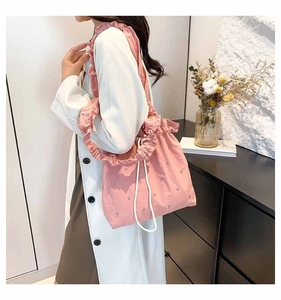 Detail of pink pleated tote bag with silver studs and white drawstring closure