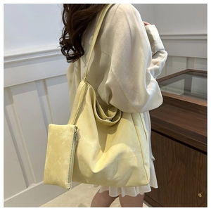 Detail of light yellow matte tote bag with matching zipper pouch and wide shoulder strap