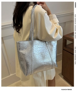 Silver metallic tote bag with crocodile embossing shown on shoulder in lifestyle scene