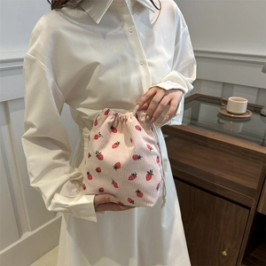 Sac seau en velours côtelé rose à motif fraise et cordon porté par un mannequin