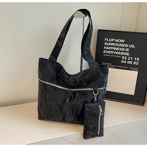 Detail of black tote bag with wrinkled texture, silver zipper and detachable pouch