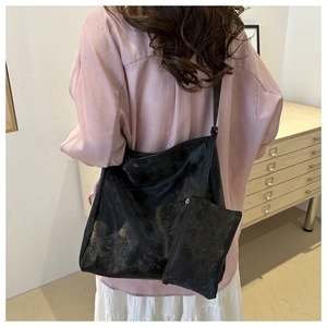 Detail of black metallic texture hobo tote bag with matching mini pouch on a model