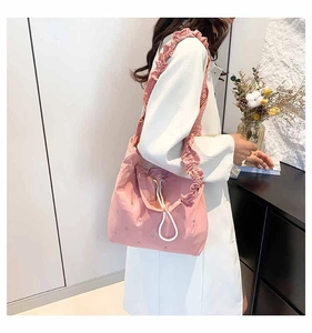 Pink pleated tote bag detail showing white drawstring and ruffled shoulder strap design