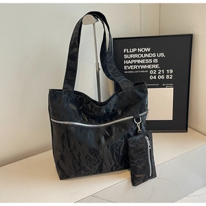 Close-up of black wrinkled texture tote bag with silver zipper and small matching pouch