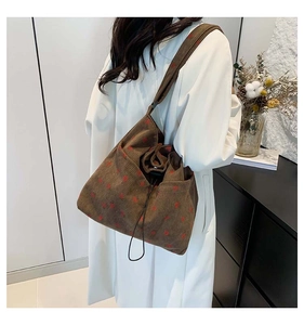 Detail of dark brown corduroy tote bag featuring red heart patterns and drawstring closure