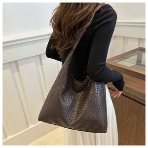 Detail of dark brown woven tote bag showing premium synthetic leather texture on a shoulder