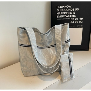 Detailed close-up of metallic silver tote bag with textured finish and matching small pouch