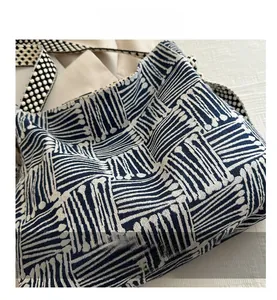 Detailed close-up of geometric pattern on woven canvas tote bag with textured straps