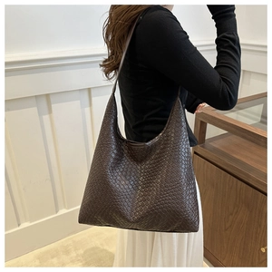 Detailed close-up of brown woven leather texture on a large stylish hobo shoulder bag