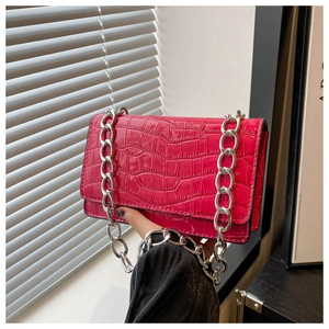 Detail of fuchsia crocodile embossed crossbody bag with thick silver metal chain strap