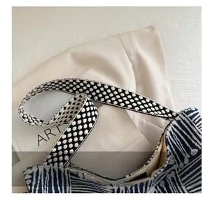 Detailed close-up of the thick woven polka dot shoulder strap and geometric canvas fabric