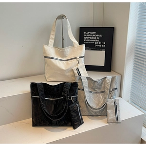 Three large tote bags in cream, black, and silver with unique crinkled texture detail
