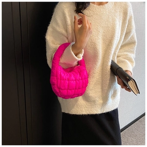 Detail of bright pink puffer bag with quilted texture and soft integrated handle