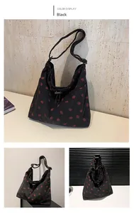 Detail of black corduroy tote bag with red strawberry pattern and drawstring closure