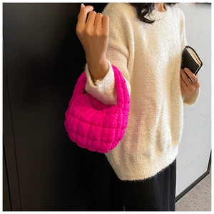 Magenta pleated cloud bag in quilted shiny nylon worn by a model in a minimalist setting