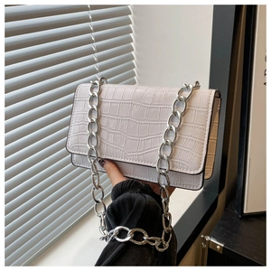 Close-up of white crocodile pattern crossbody bag with thick silver chain strap