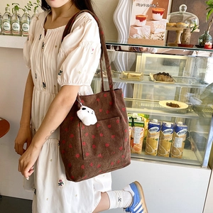 Corduroy tote bag with strawberry print and plush charm shown in a lifestyle scene