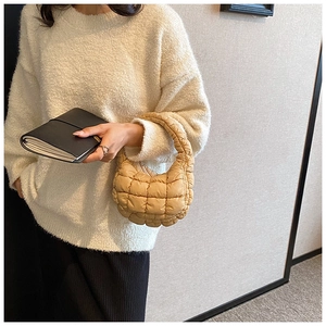 Detail of khaki quilted cloud handbag texture held by a model in casual outfit