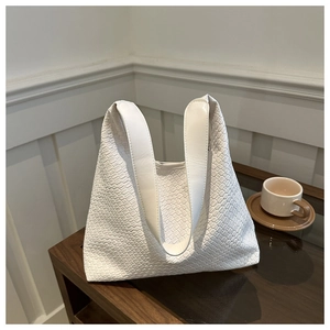 Detailed view of white woven hobo bag showing refined texture and minimalist handle design