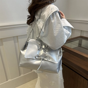 Borsa a tracolla argento metallizzato con fiocco e catena indossata da una modella