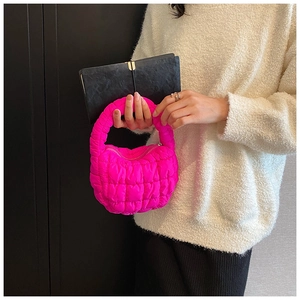 Close-up of a vibrant neon pink quilted cloud bag featuring unique ruched texture and handle