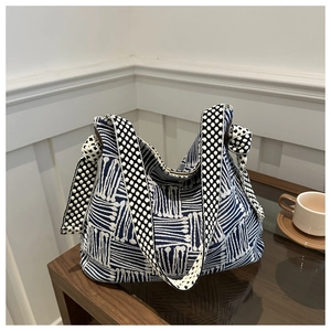 Detail view of canvas tote bag with blue geometric pattern and polka dot strap