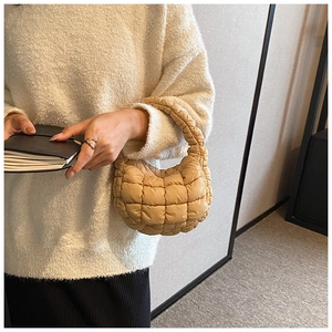Detail of beige quilted cloud bag texture and soft nylon handle held by a model
