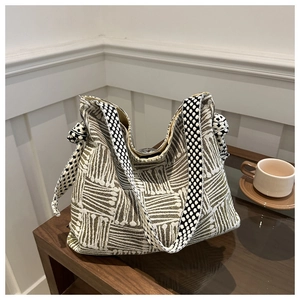 Detail of olive green woven tote bag with wide patterned strap and knot accents