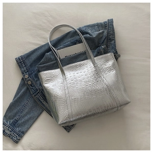 Macro shot of silver metallic tote bag featuring realistic crocodile embossed texture