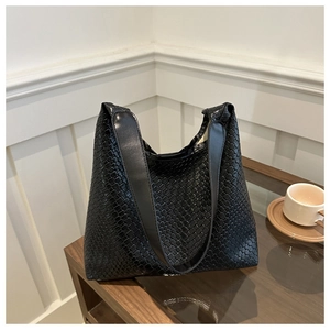 Detail view of black woven leather tote bag texture and smooth shoulder straps