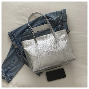 Detailed macro view of large silver tote bag with crocodile texture on white fabric