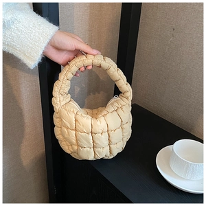 Detail view of beige quilted cloud handbag featuring half-moon shape and metal zipper