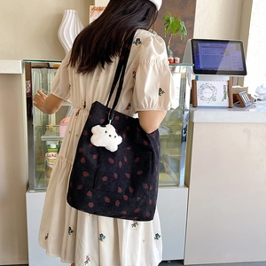 Close-up of black corduroy tote bag with strawberry print and star plush pendant detail
