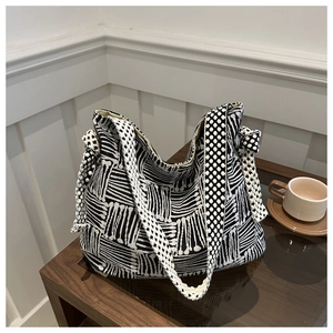 Detail of large canvas tote bag with black and white geometric patterns and knot accents