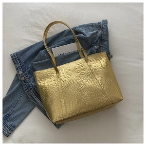 Detail of gold tote bag with crocodile texture embossing and metallic finish