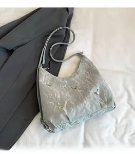 Détail du sac hobo plissé gris avec papillons argentés et bandoulière réglable