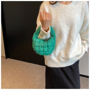 Detail of emerald green quilted crescent bag with bubble texture and stylish handle