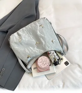 Détail du sac à bandoulière plissé gris avec papillons en métal et grand espace