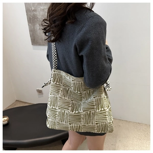 Detail of knit shoulder bag with green geometric patterns and polka dot strap